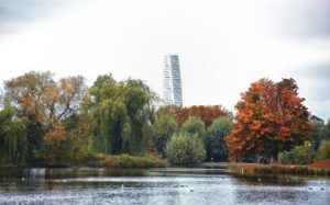 The iconic skyscraper building Turning Torso in the background behind Autumn trees in Pildammsparken in Malmo, Sweden. Filtered image with soft effect.